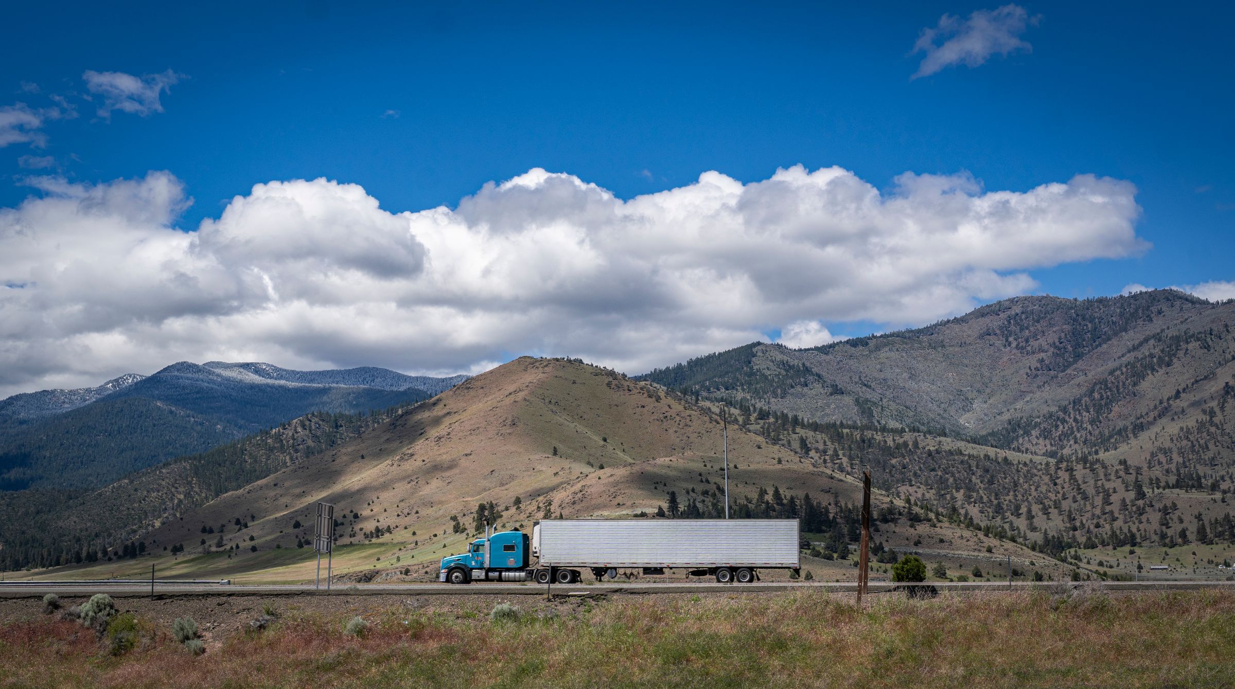 A tractor-trailer hauling a reefer trailer on a mountain highway.